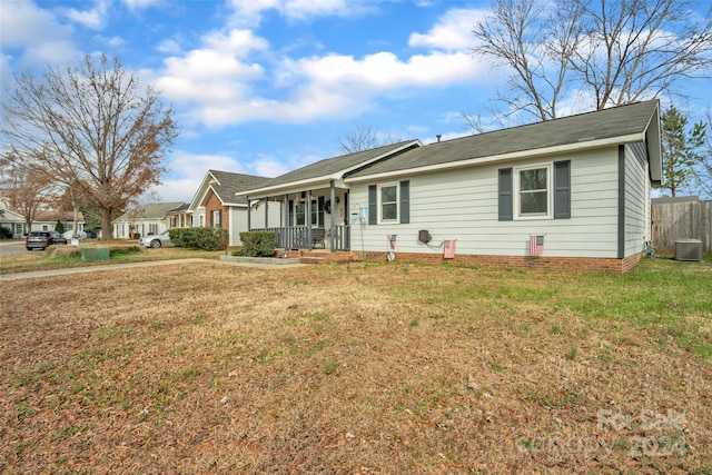 ranch-style house featuring cooling unit, covered porch, and a front yard