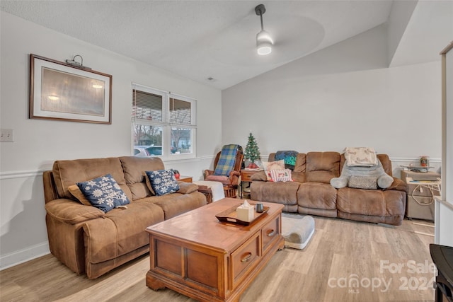 living room featuring a textured ceiling, ceiling fan, light hardwood / wood-style flooring, and vaulted ceiling