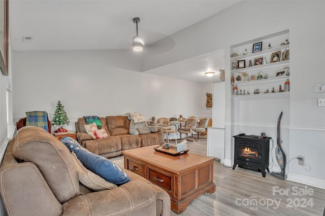 living room featuring ceiling fan, light hardwood / wood-style floors, a wood stove, and vaulted ceiling