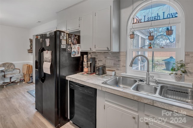 kitchen with decorative backsplash, sink, black appliances, light hardwood / wood-style flooring, and white cabinets