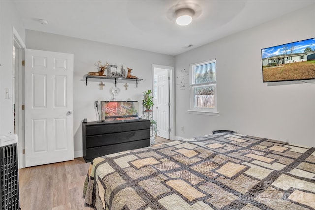 bedroom with heating unit, ceiling fan, and light hardwood / wood-style flooring