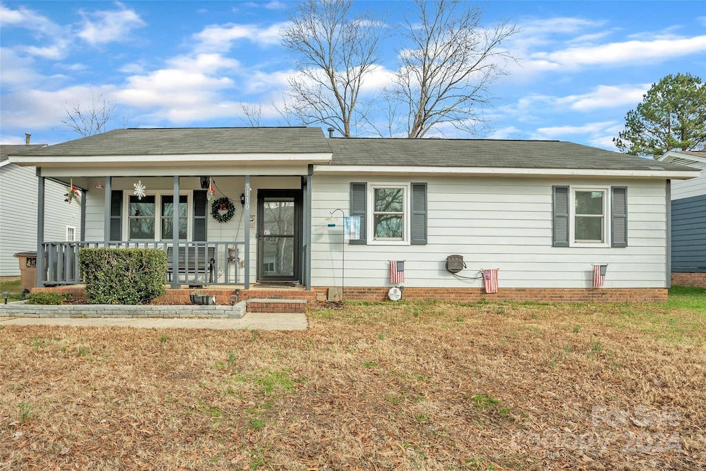 ranch-style home featuring covered porch and a front yard