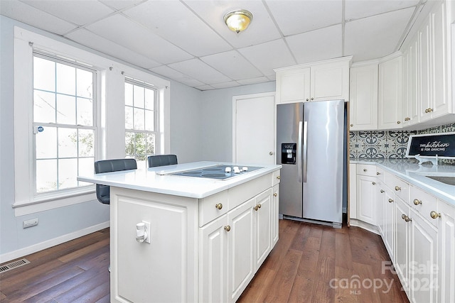 kitchen with dark wood-type flooring, a kitchen island, stainless steel fridge with ice dispenser, electric cooktop, and white cabinets