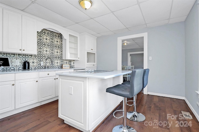 kitchen featuring tasteful backsplash, a breakfast bar, dark wood-type flooring, white cabinets, and a center island