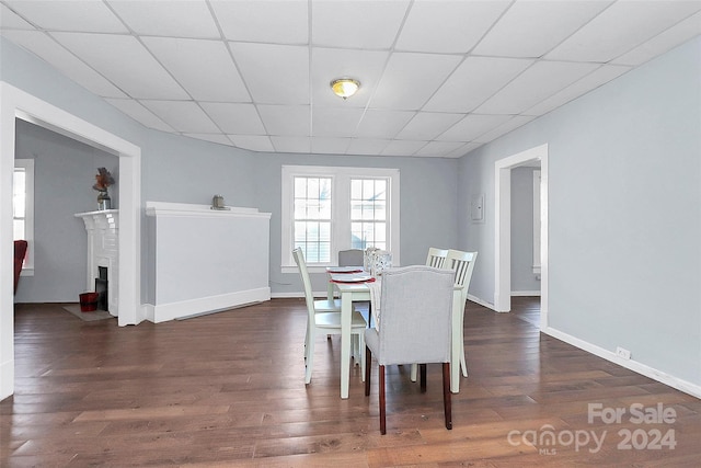 dining room with a drop ceiling and dark wood-type flooring