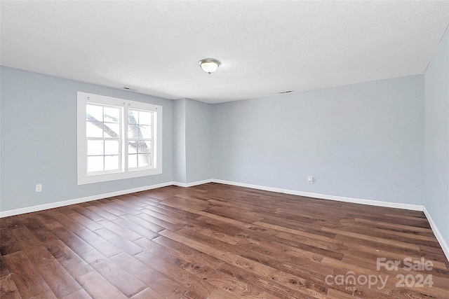 unfurnished room featuring a textured ceiling and dark hardwood / wood-style floors