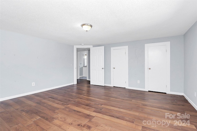 spare room featuring a textured ceiling and dark wood-type flooring