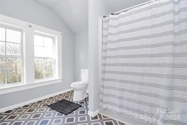 bathroom featuring toilet, a shower with shower curtain, vaulted ceiling, and a wealth of natural light