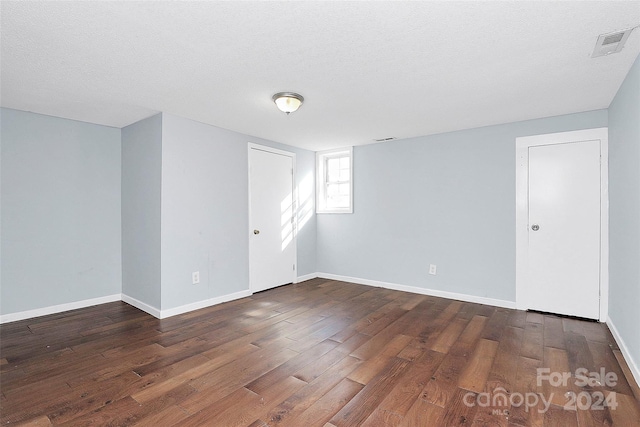 spare room with dark hardwood / wood-style flooring and a textured ceiling