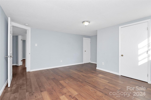 unfurnished room featuring a textured ceiling and dark hardwood / wood-style flooring