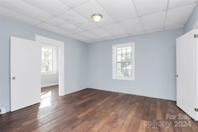 spare room with a paneled ceiling, plenty of natural light, and dark wood-type flooring