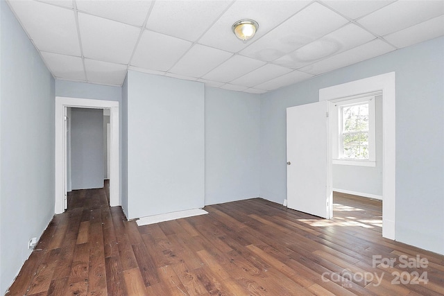 spare room featuring a paneled ceiling and dark hardwood / wood-style floors