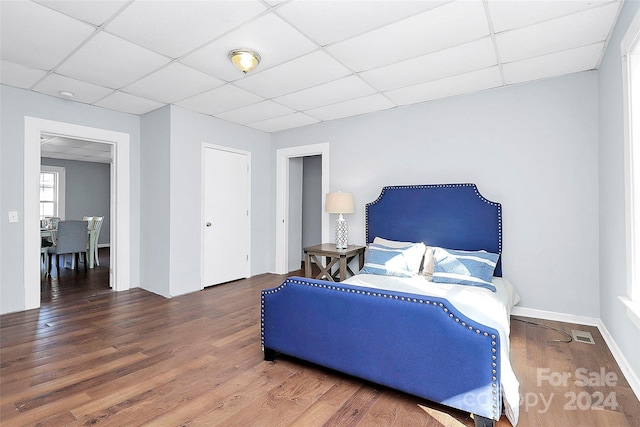 bedroom with a drop ceiling and dark wood-type flooring