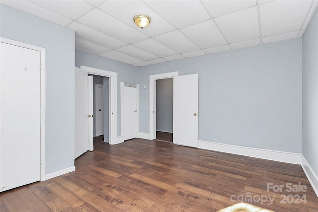 unfurnished bedroom with a drop ceiling and dark hardwood / wood-style floors