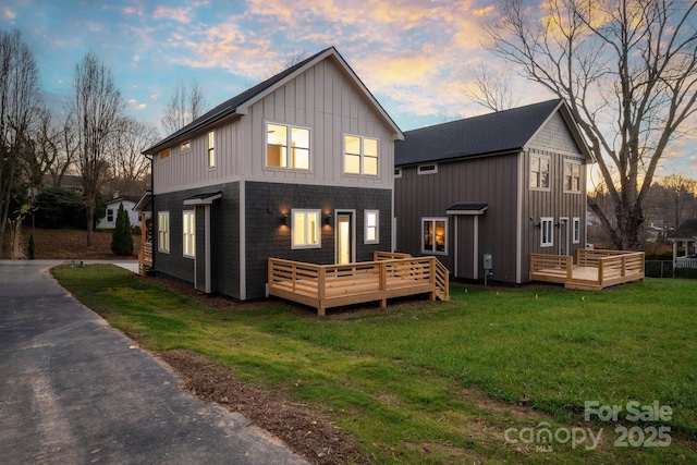 back house at dusk with a lawn and a wooden deck