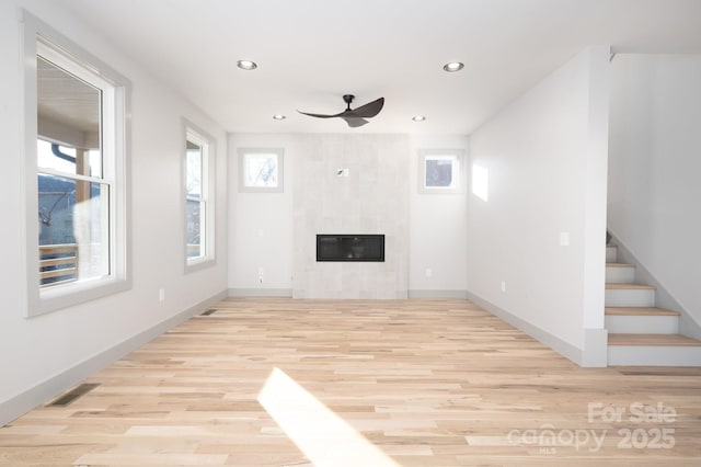 unfurnished living room featuring ceiling fan, a fireplace, and light hardwood / wood-style flooring