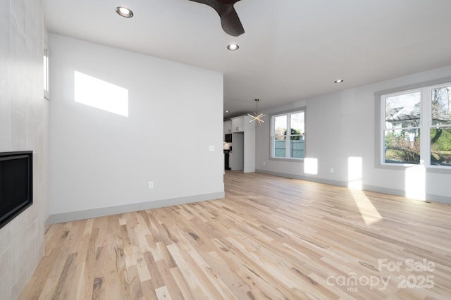 unfurnished living room featuring ceiling fan and light hardwood / wood-style floors