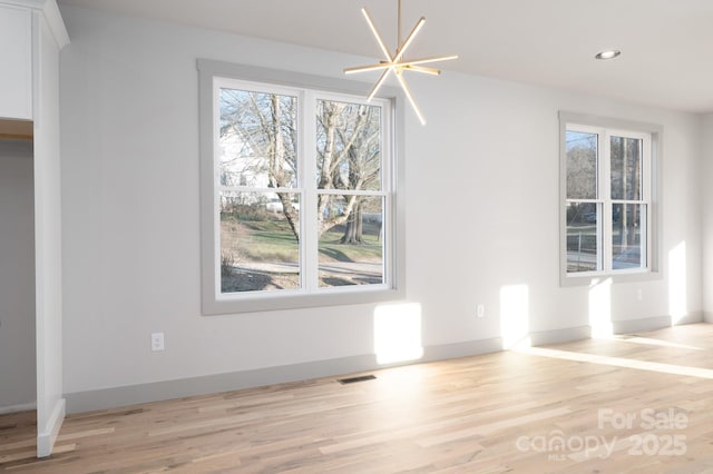 unfurnished dining area featuring light hardwood / wood-style flooring and an inviting chandelier