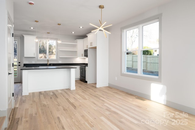 kitchen featuring a center island, decorative light fixtures, white cabinetry, and light hardwood / wood-style flooring