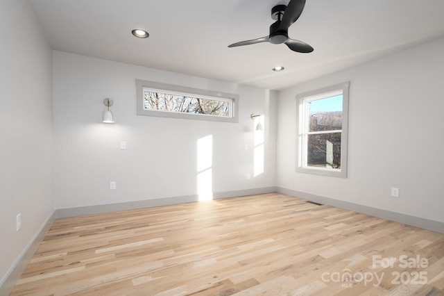 spare room with a wealth of natural light, ceiling fan, and light hardwood / wood-style floors