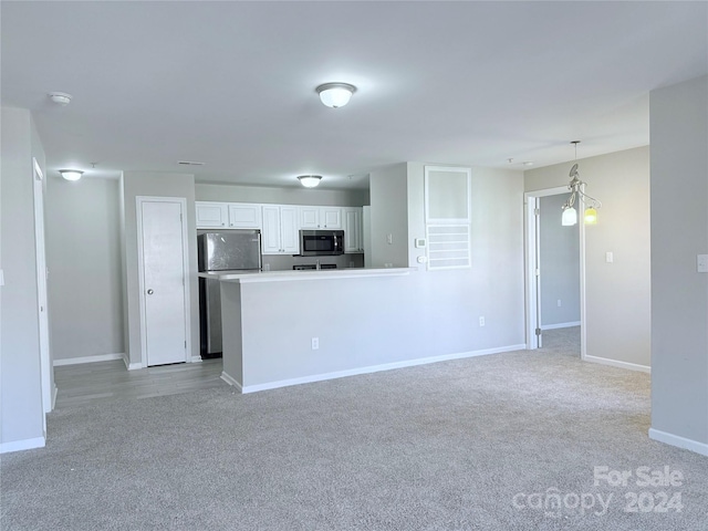 kitchen with light carpet, decorative light fixtures, appliances with stainless steel finishes, a notable chandelier, and white cabinetry