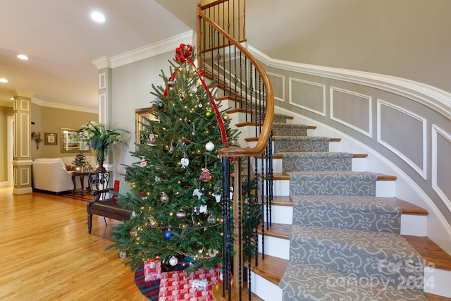 stairs featuring hardwood / wood-style flooring, crown molding, and decorative columns