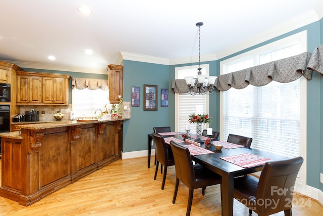 dining room featuring ornamental molding, an inviting chandelier, a healthy amount of sunlight, and light hardwood / wood-style floors