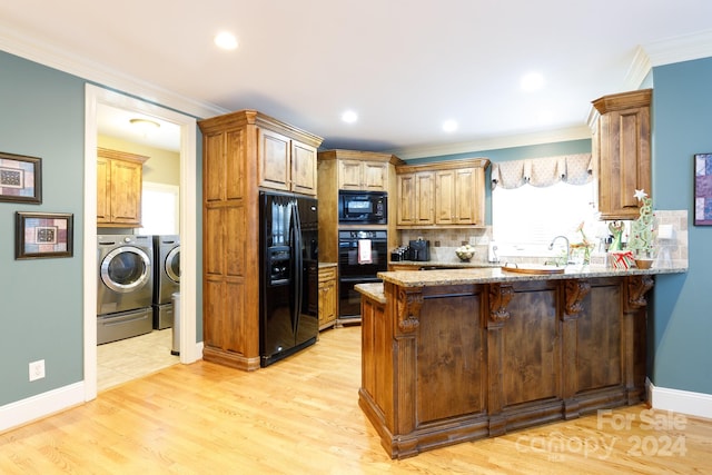 kitchen with black appliances, washer and clothes dryer, a kitchen breakfast bar, and light hardwood / wood-style flooring