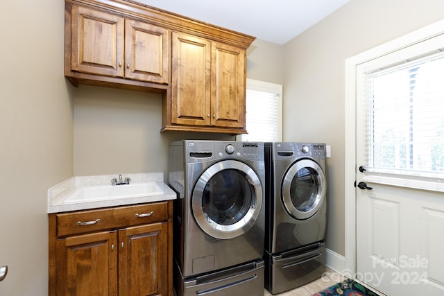 clothes washing area featuring cabinets, sink, a healthy amount of sunlight, and independent washer and dryer