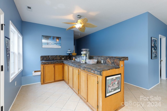 kitchen with kitchen peninsula, light tile patterned floors, ceiling fan, and sink