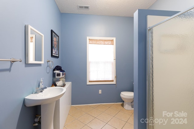 bathroom with sink, walk in shower, tile patterned flooring, a textured ceiling, and toilet