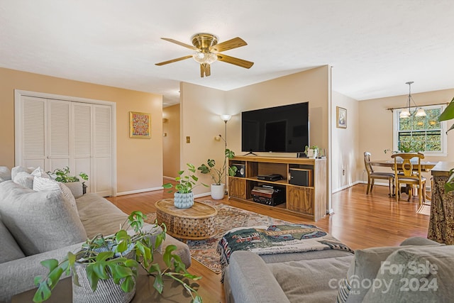 living room with light hardwood / wood-style flooring and ceiling fan with notable chandelier