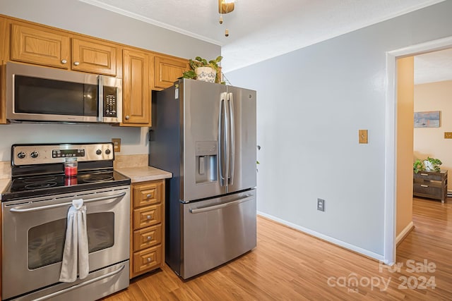 kitchen featuring a textured ceiling, light wood-type flooring, stainless steel appliances, and ornamental molding