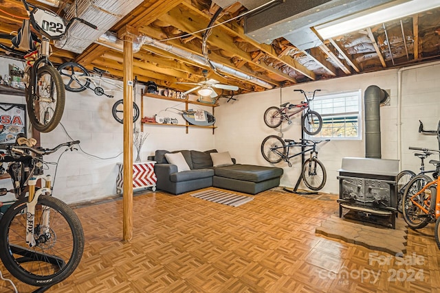 basement featuring ceiling fan, a wood stove, and parquet flooring