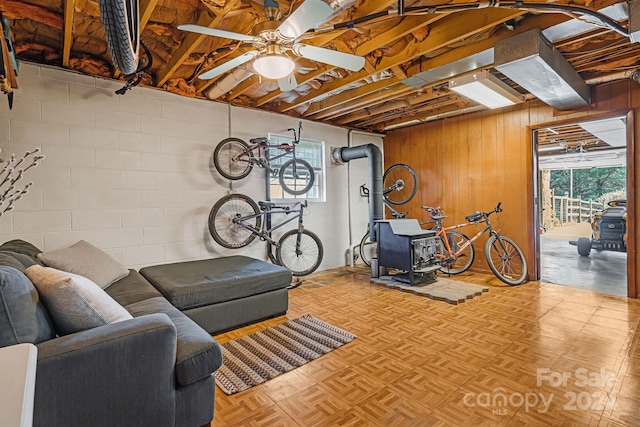 workout room featuring light parquet flooring, a wood stove, ceiling fan, and wooden walls