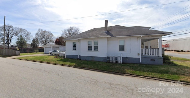 view of side of property featuring an outbuilding, a yard, a garage, and covered porch