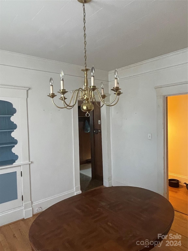 unfurnished dining area with hardwood / wood-style floors, a notable chandelier, and ornamental molding