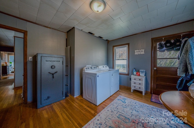 laundry area featuring washing machine and dryer, hardwood / wood-style flooring, crown molding, and wood walls