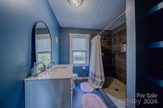 bathroom with tile patterned floors, toilet, vanity, and walk in shower