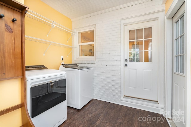 clothes washing area featuring dark hardwood / wood-style floors, washer and clothes dryer, and brick wall