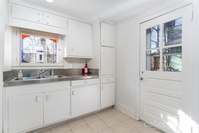 kitchen with white cabinets, stainless steel counters, light tile patterned floors, and sink