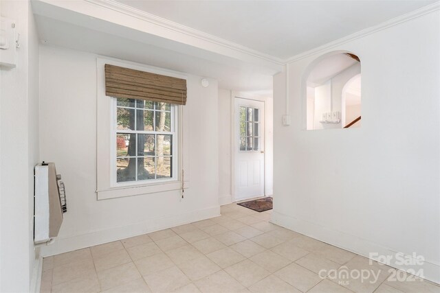 tiled empty room with heating unit and ornamental molding