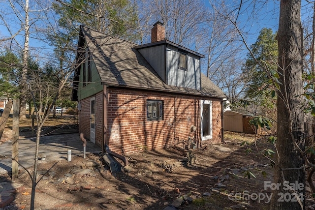 103 Pine St, Black Mountain, NC 28711 - view of home's exterior with brick siding, a chimney, a storage shed, and a shingled roof