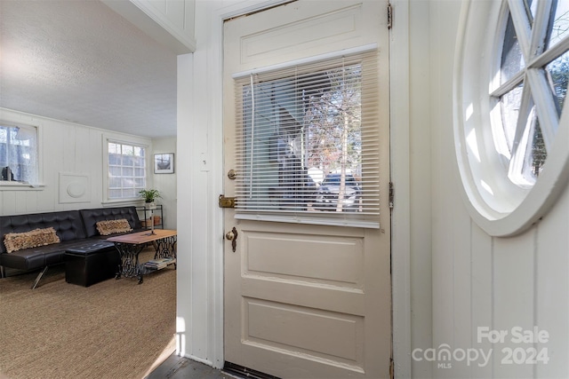 doorway with carpet flooring and a textured ceiling