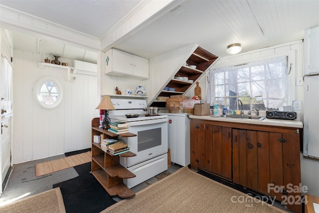 kitchen featuring electric range, wooden walls, and sink