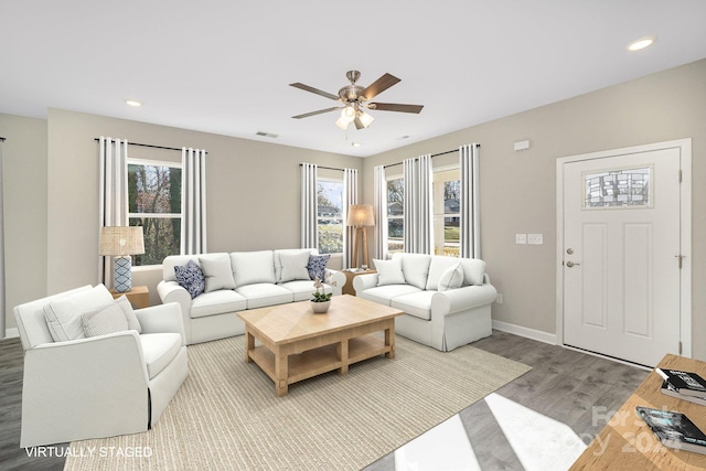 living room with wood-type flooring, ceiling fan, and a healthy amount of sunlight