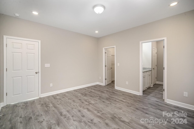 unfurnished bedroom featuring ensuite bathroom, light wood-type flooring, and a closet