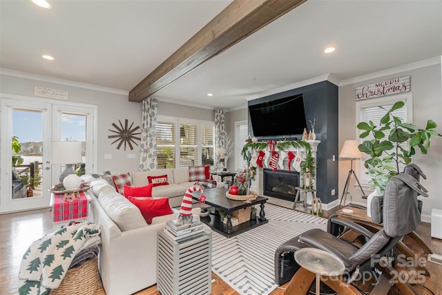 living room with beamed ceiling, ornamental molding, a fireplace, and a wealth of natural light