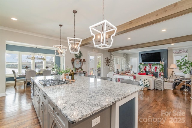 kitchen with beamed ceiling, light stone countertops, stainless steel gas cooktop, and pendant lighting