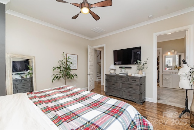 bedroom with crown molding, dark wood-type flooring, ceiling fan, and ensuite bath